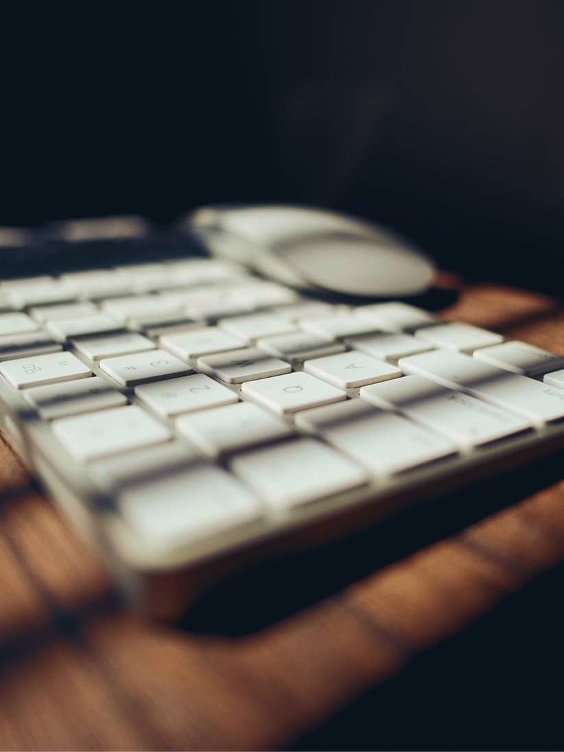 Cztery osoby pracujące na laptopach przy drewnianym stole w rustykalnym pokoju z wiszącą oprawą oświetleniową.